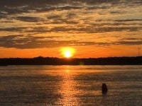 the sun is setting over the water
