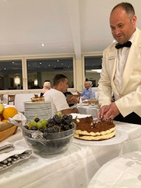 a man in a tuxedo cutting a cake