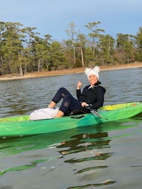 a woman in a green kayak with a santa hat on her head